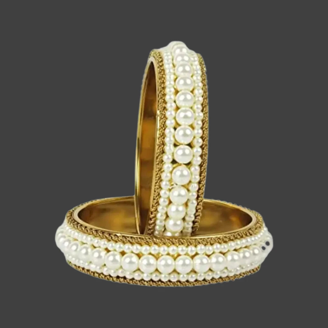  Ethnic Gold Tone Pearl Broad Kada Pair Bangle Set For Women
Color: White and gold
Sizes: 2.6, 2.8 
Style:  Bangle-Style 
Ideal Gift : Loved once - Mom, Wifre, Girlfriend, Syste, daughter.
Looks: Bollywood Diva Looks
Material:  Alloy
Stone Type: Pearls
 Country of Origin: INDIA
This Ethnic Gold Tone Pearl Broad Kada Pair Bangle Set For Women is a statement accessory that adds elegance and sophistication to any outfit. The gold tone and pearl accents create a timeless and
